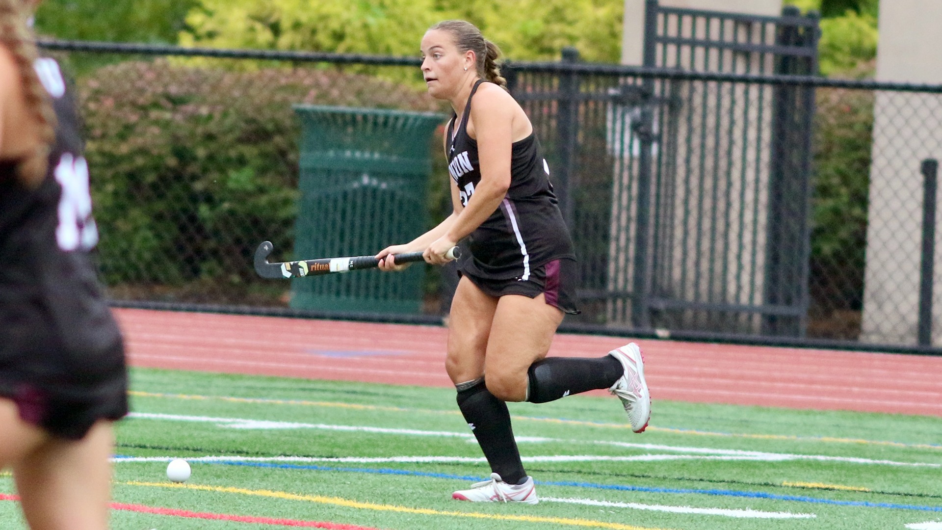 A field hockey player looks up attempting to pass.