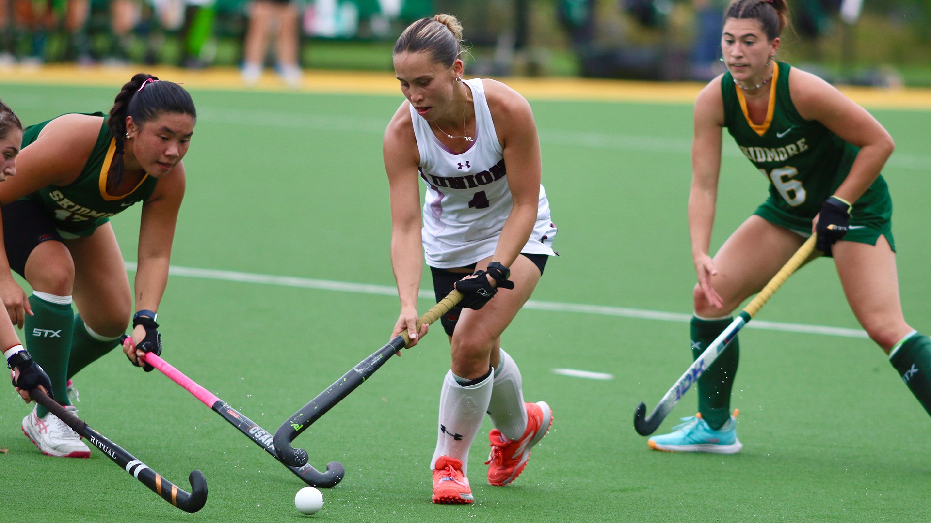 A field hockey player stickhandles through defenders.