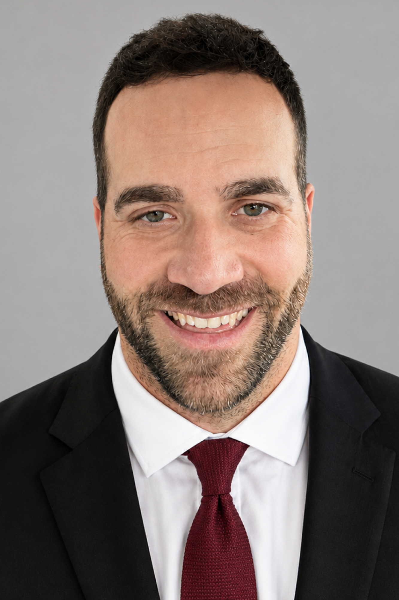 headshot of a man wearing a suit and garnet-colored tie