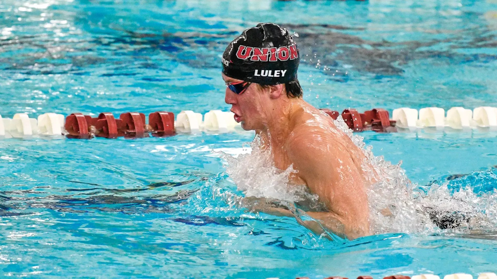 men's swimmer performing the breaststroke wearing a black swim cap that reads 