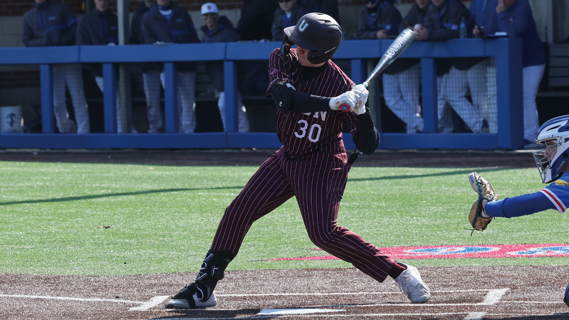 left-handed baseball player beginning his swing, wearing a garnet-colored pinstripe jersey and the number 30