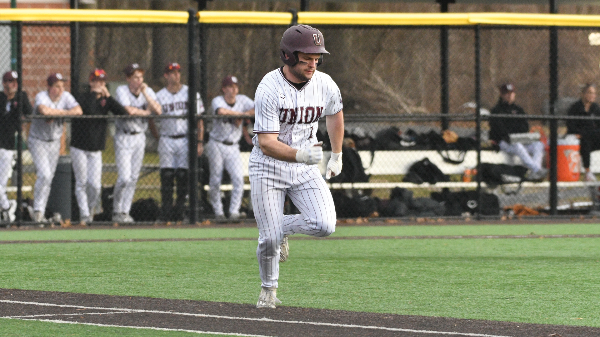 a baseball player wearing white pinstripes running to first base