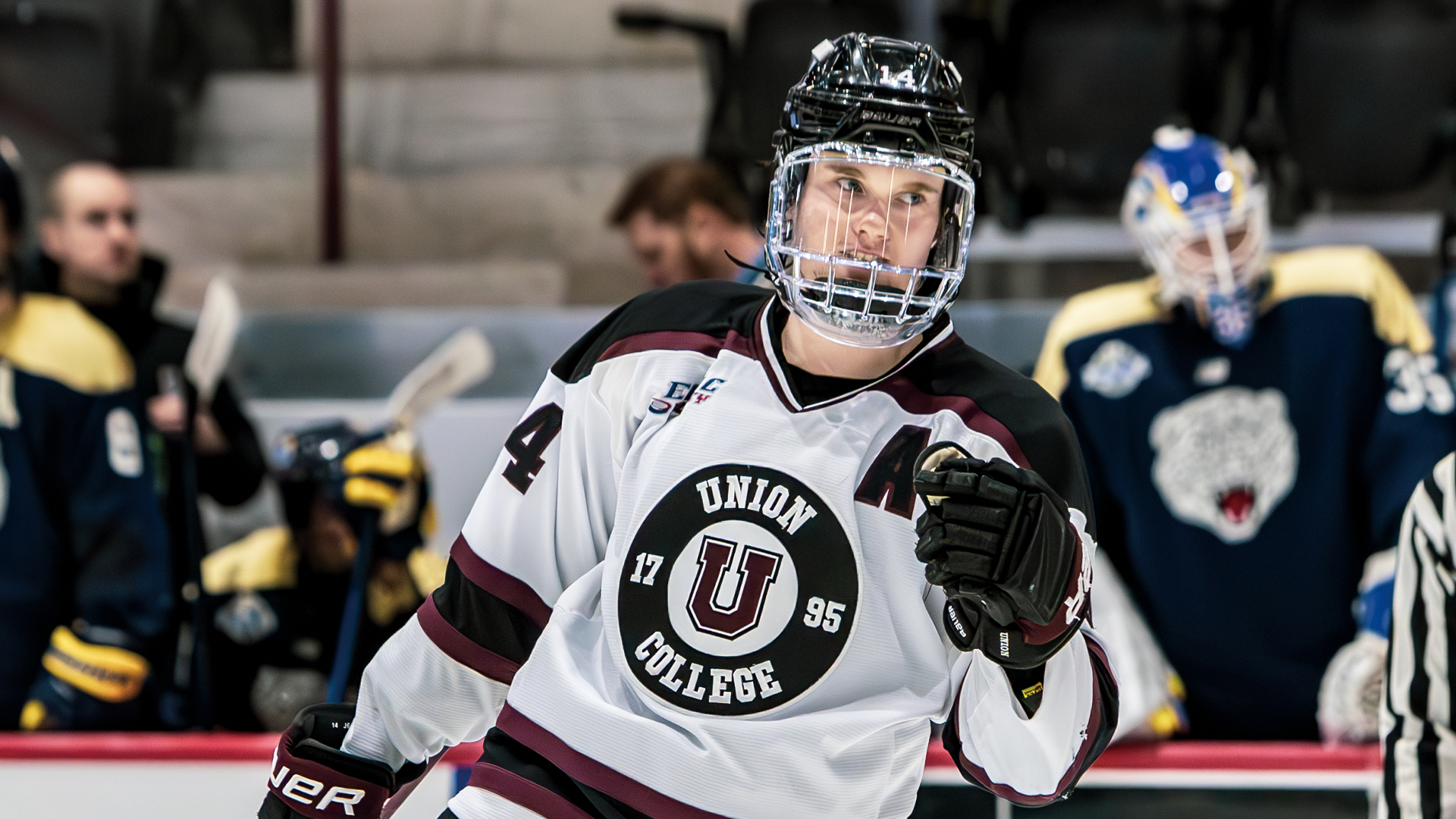 a close-up picture of a men's hockey player with his left fist our, about to fist-bump a teammate