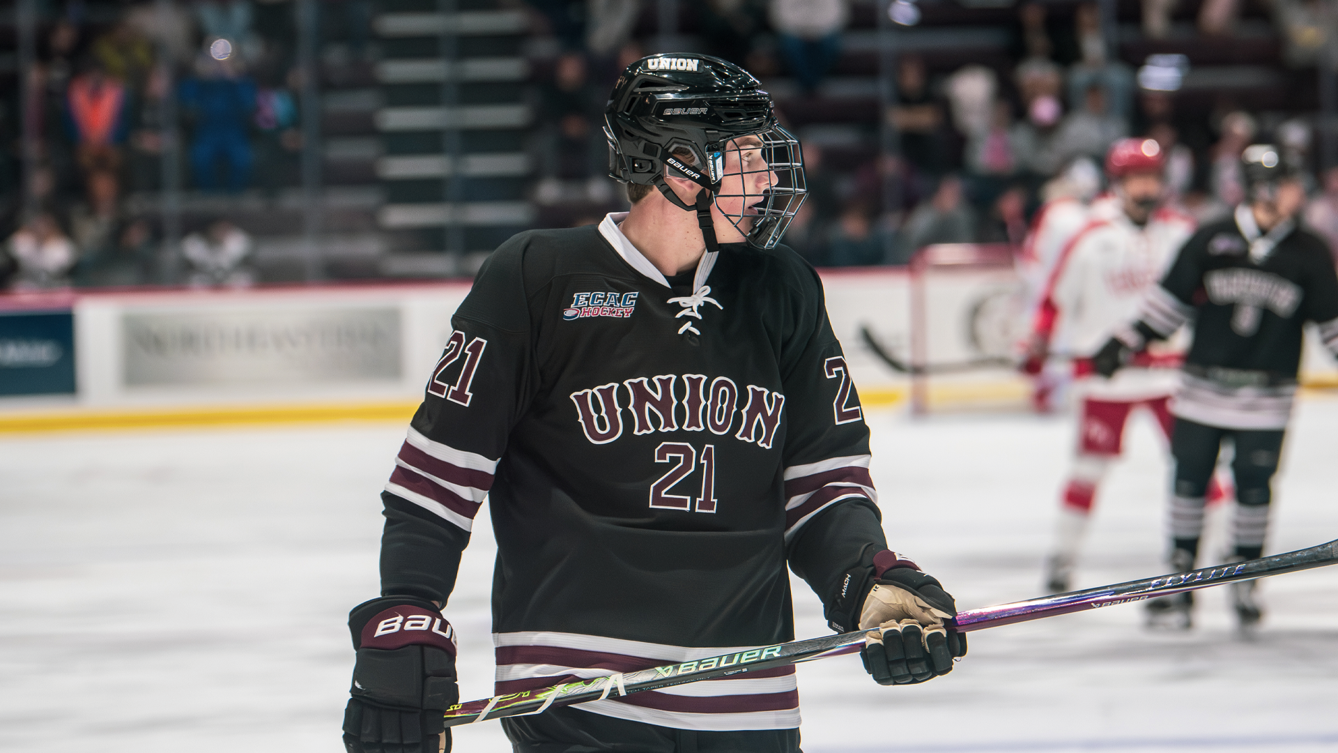 a photo of a men's hockey player from the waist up, with the player wearing an all-black uniform that reads 