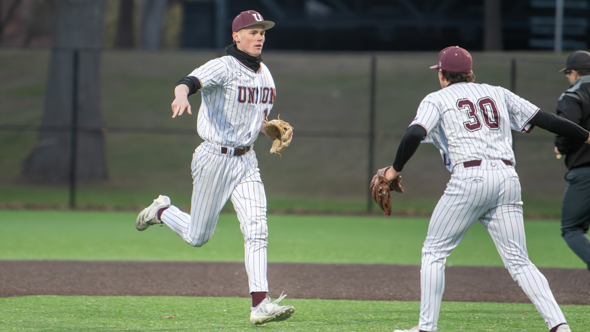 two baseball players running towards each other and preparing for a 