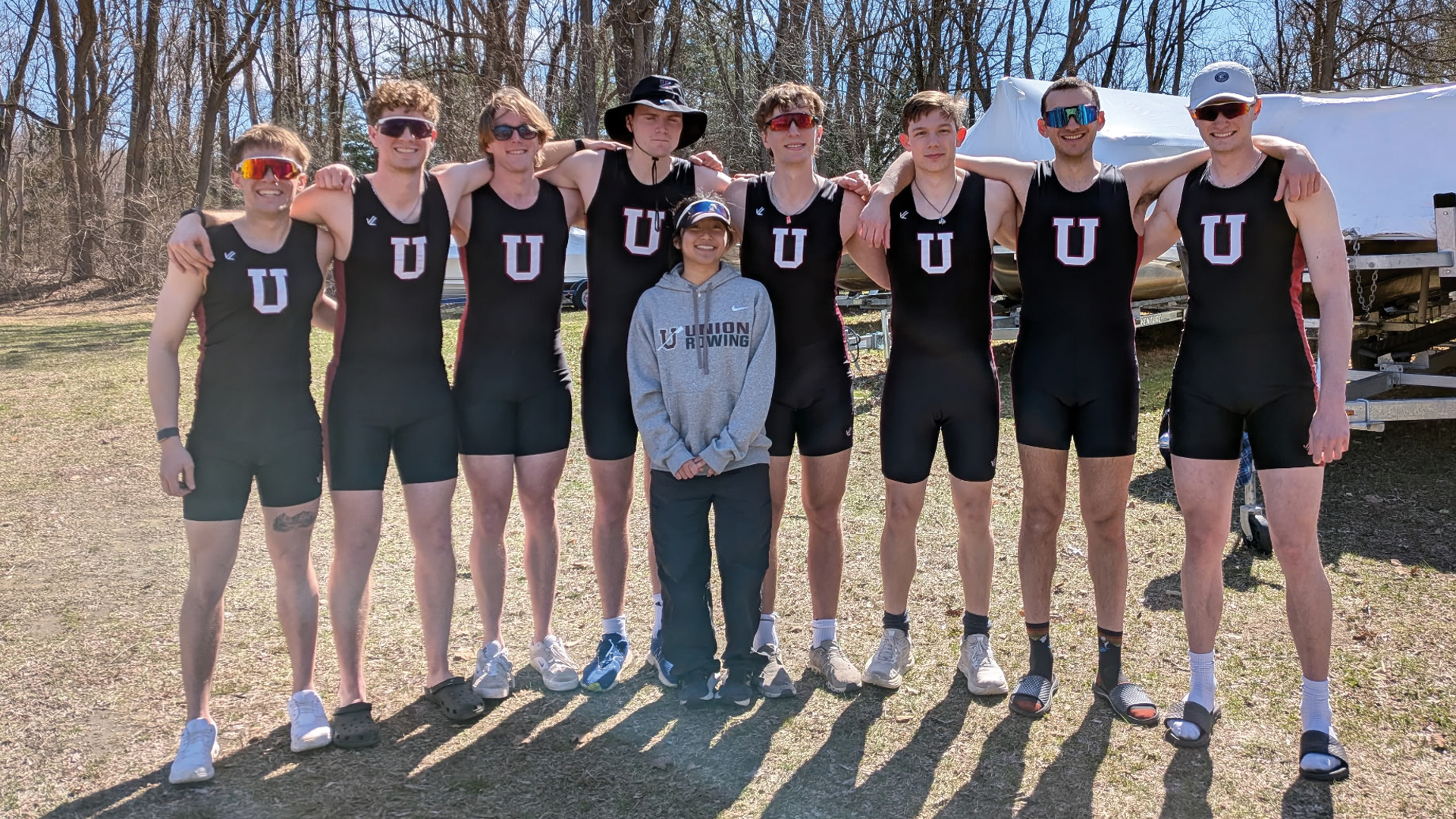 a men's crew team standing for a group picture, with their arms around each other