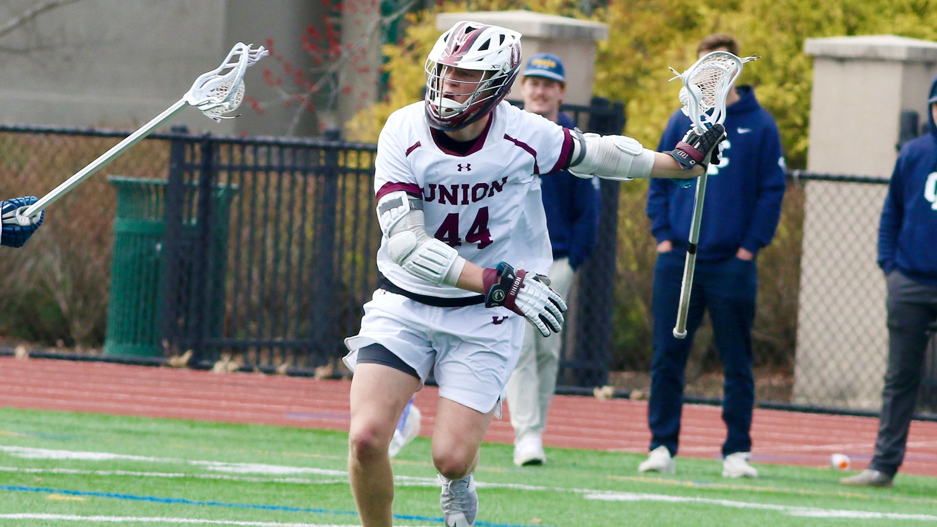 A Union lacrosse played cradling the ball in front of a defender.