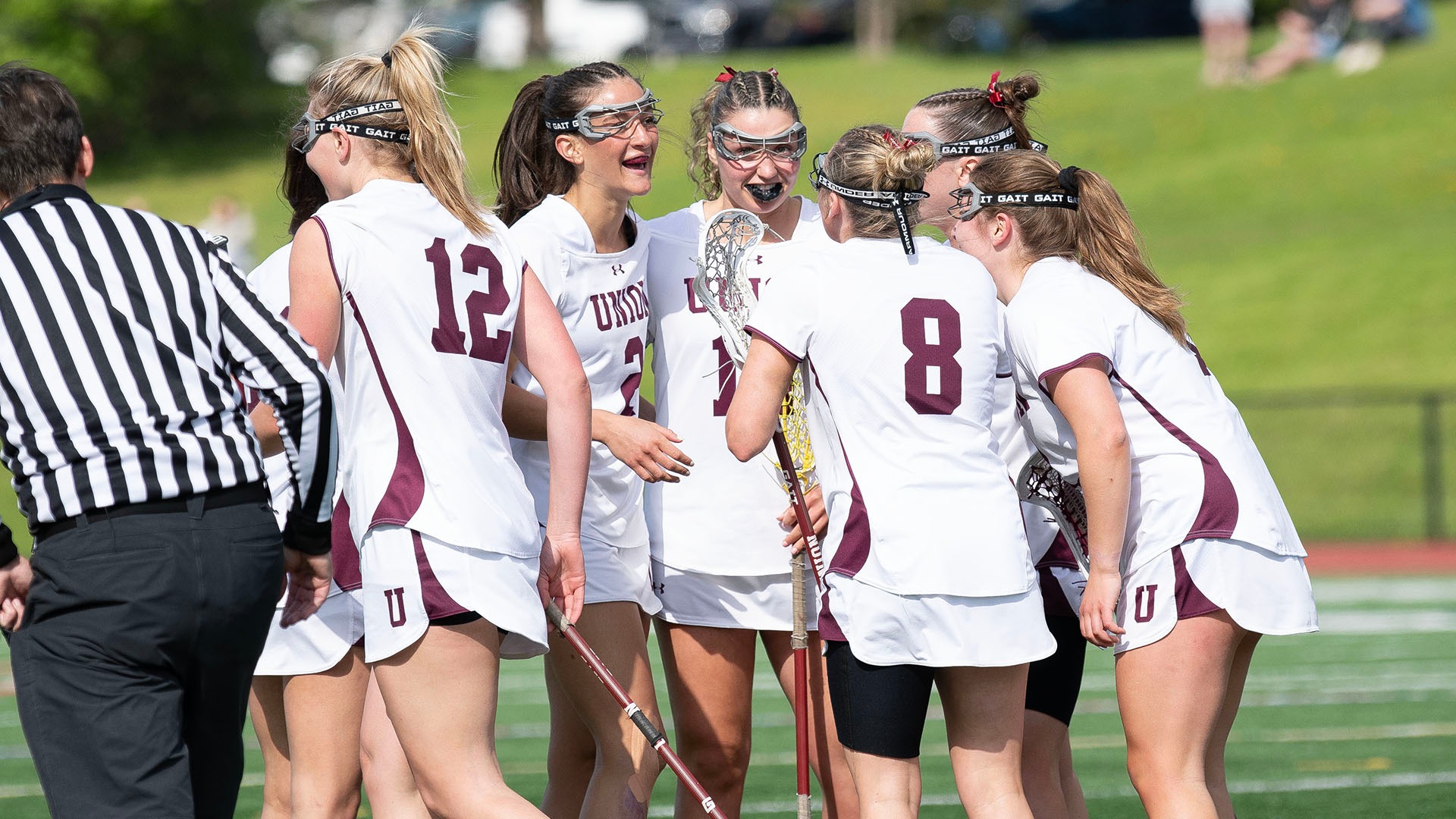 Smiling women's lacrosse players after a goal.
