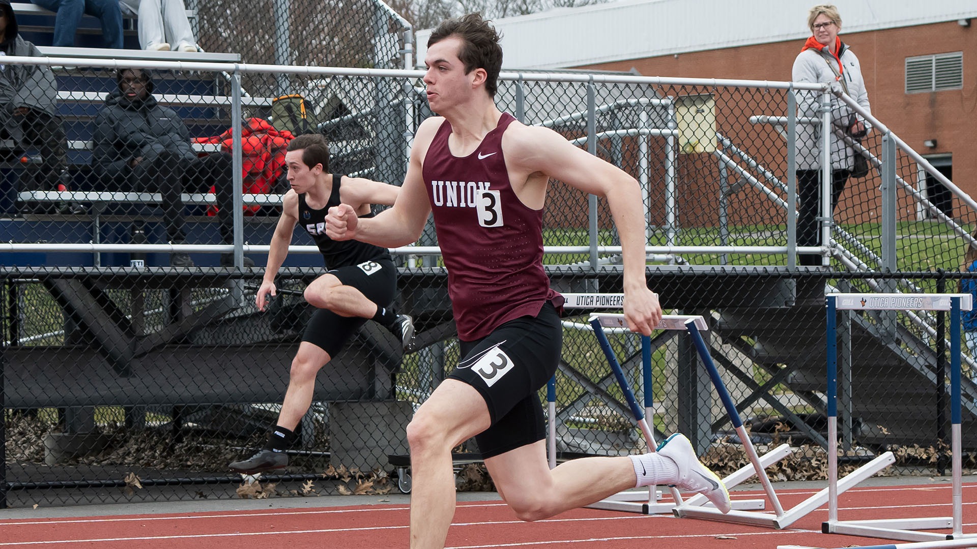 A runner preparing to leap a hurdle in a track meet.