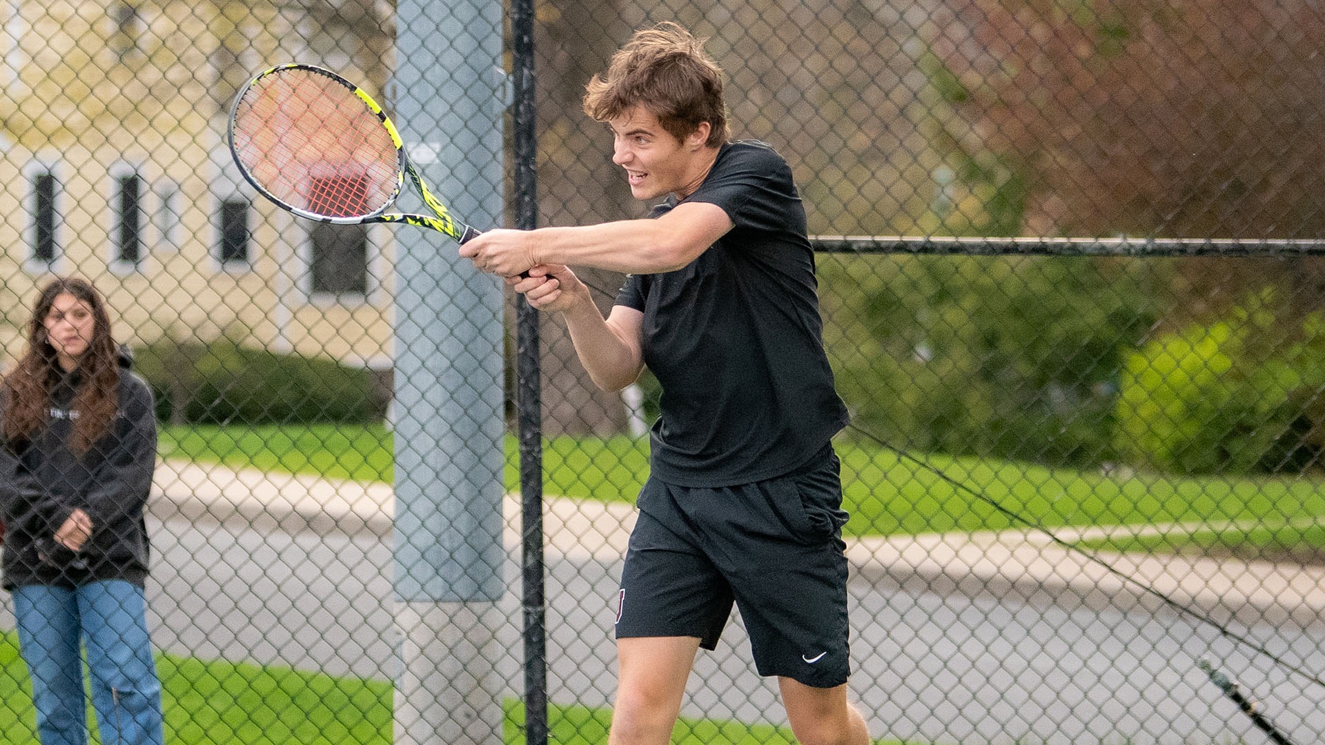 A Union tennis player hits a backhand shot