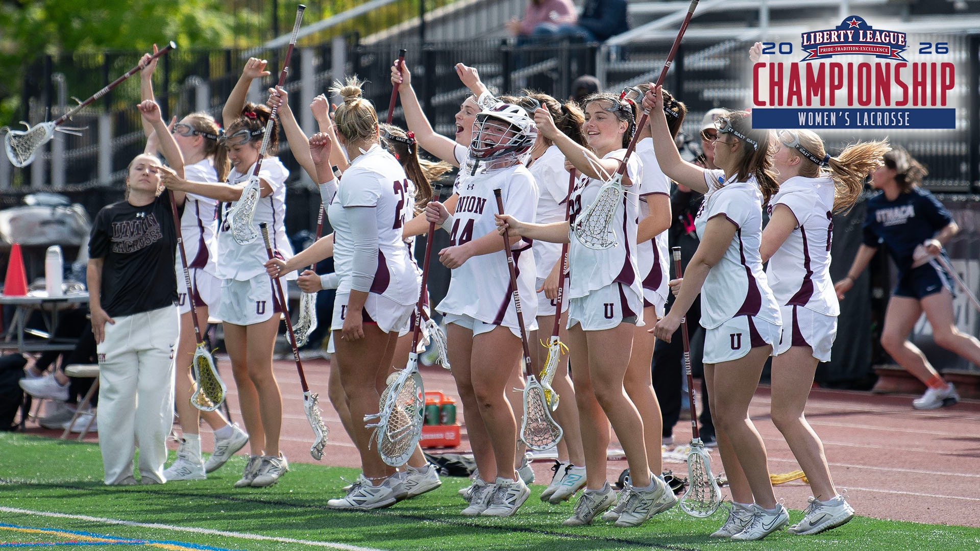 Lacrosse players celebrating a goal by shaking their hands in the air, with a Liberty League WLAX Championship logo in the corner