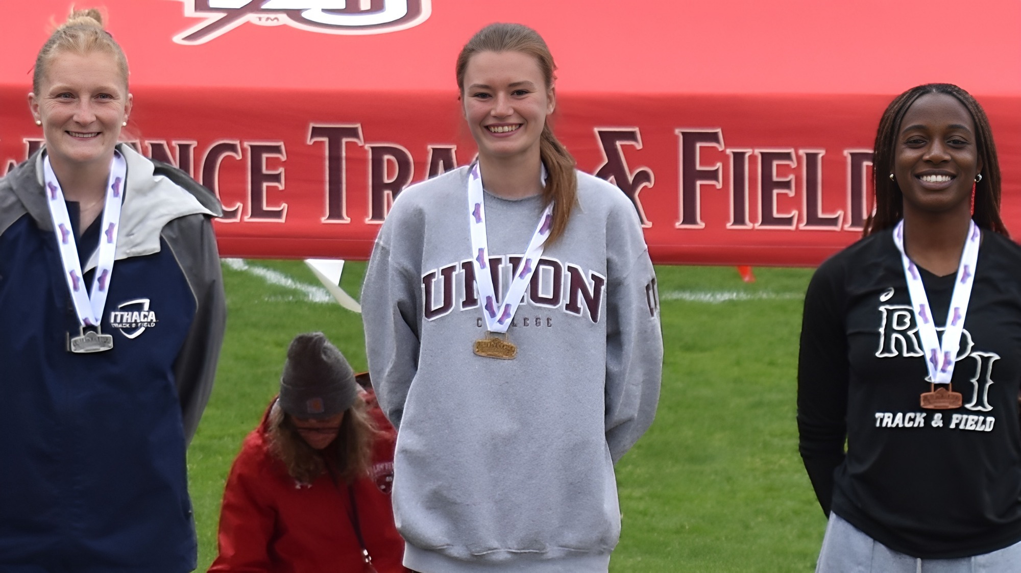 Women smiling to the camera on the podium for the high jump