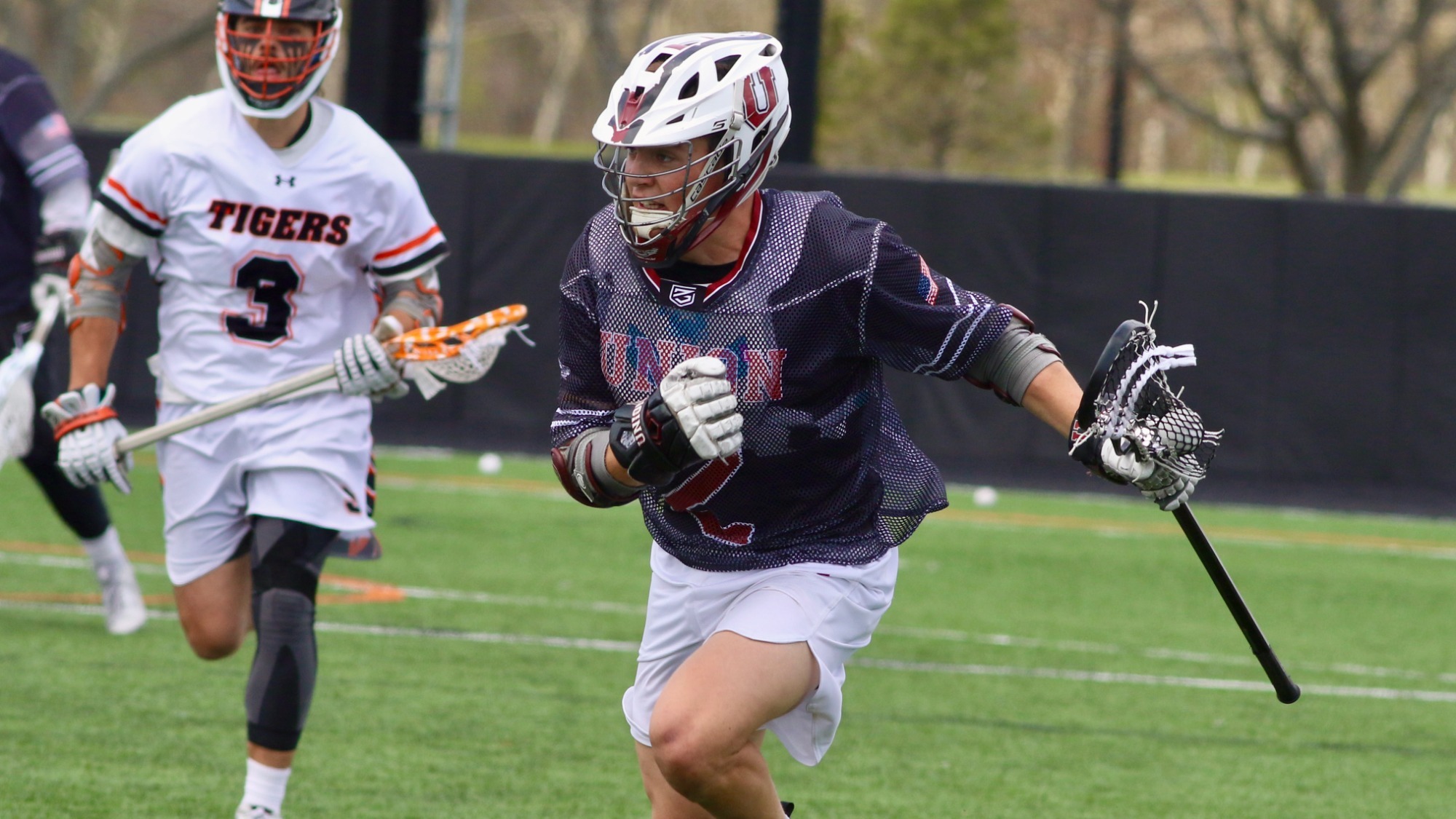 A Union lacrosse player runs up the field with the ball in his stick.