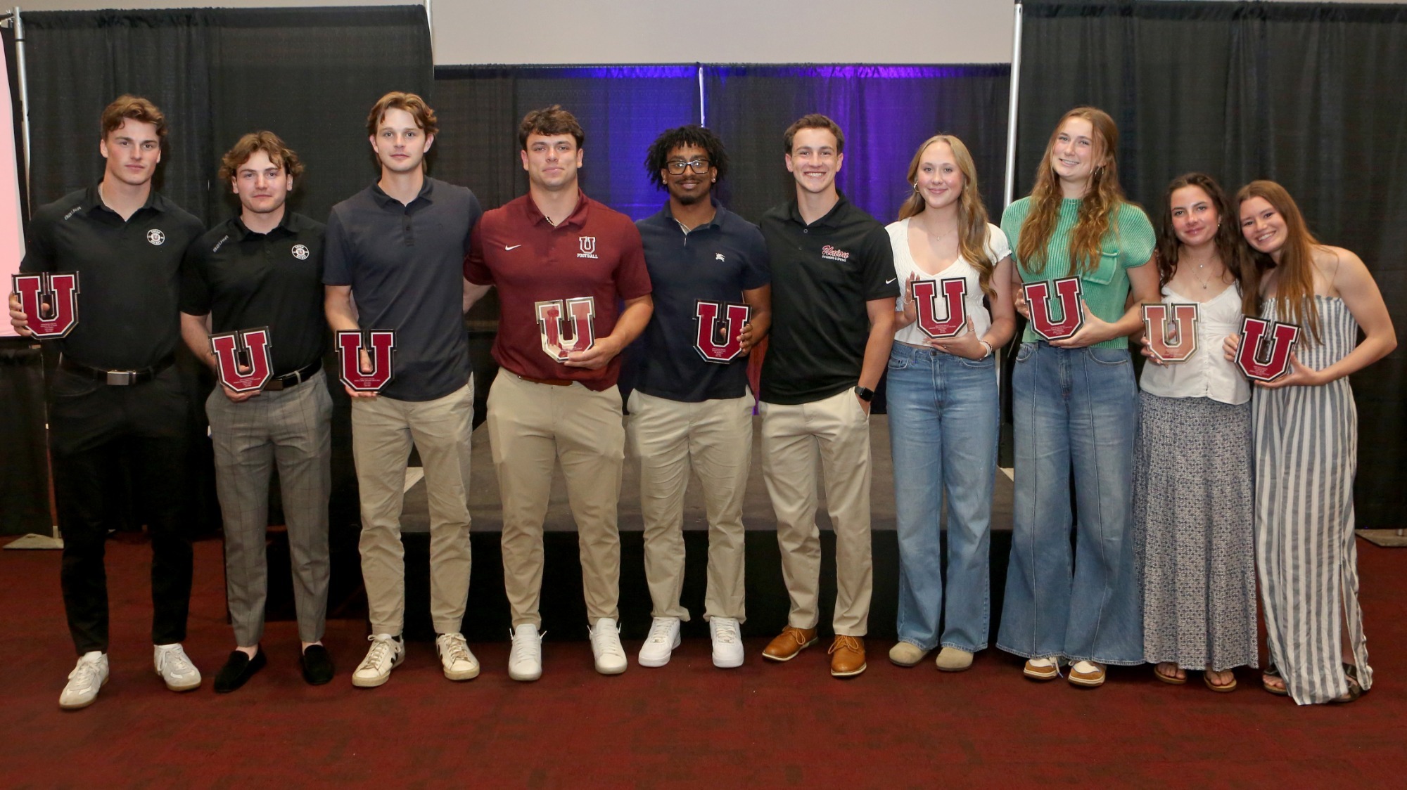 Students smiling at the camera holding Block U awards.