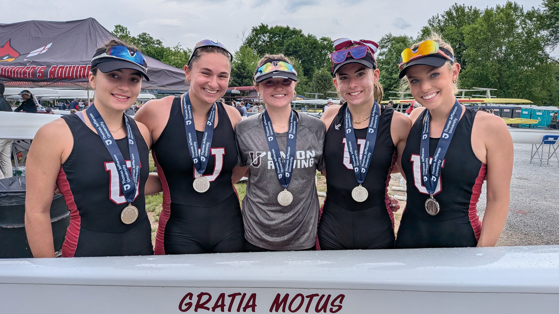 five members of the women's crew team wearing silver medals