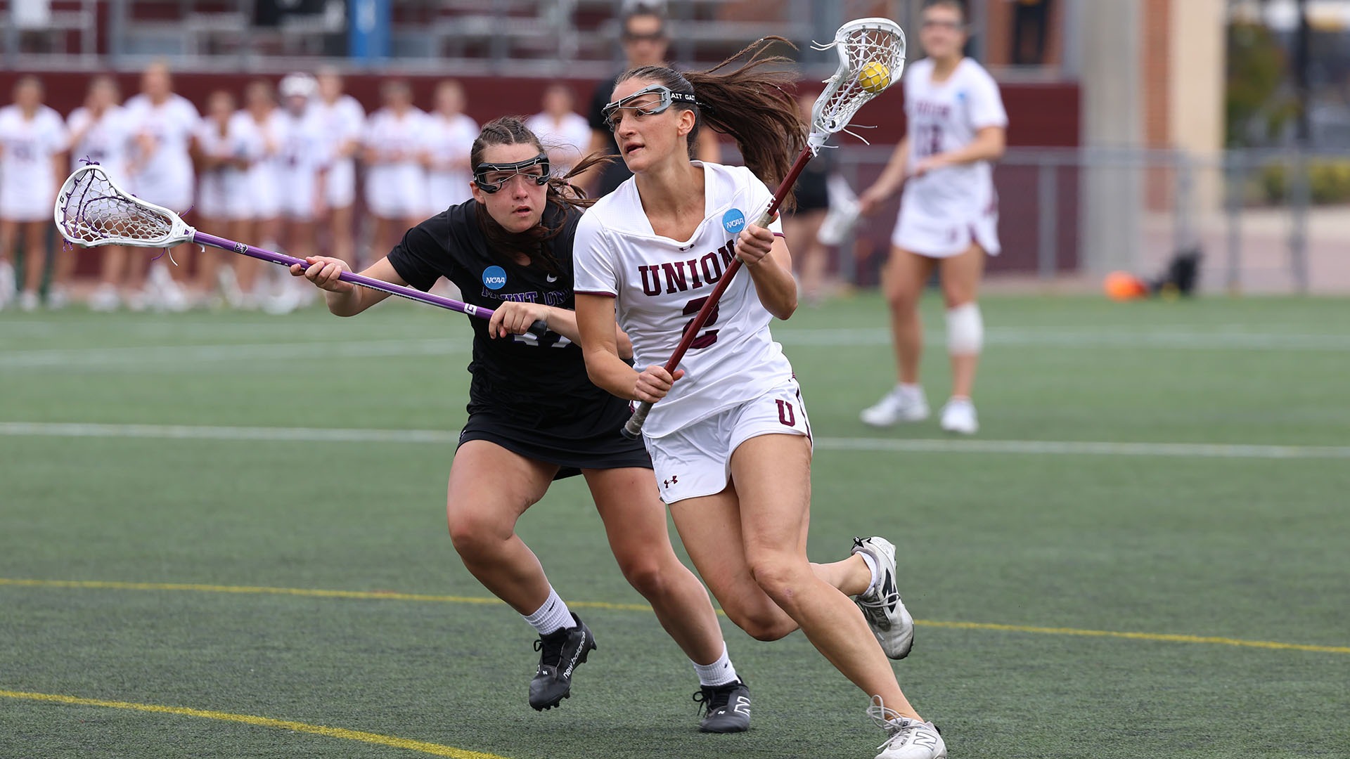 A Union lacrosse player runs by an opponent on the way to scoring a goal.