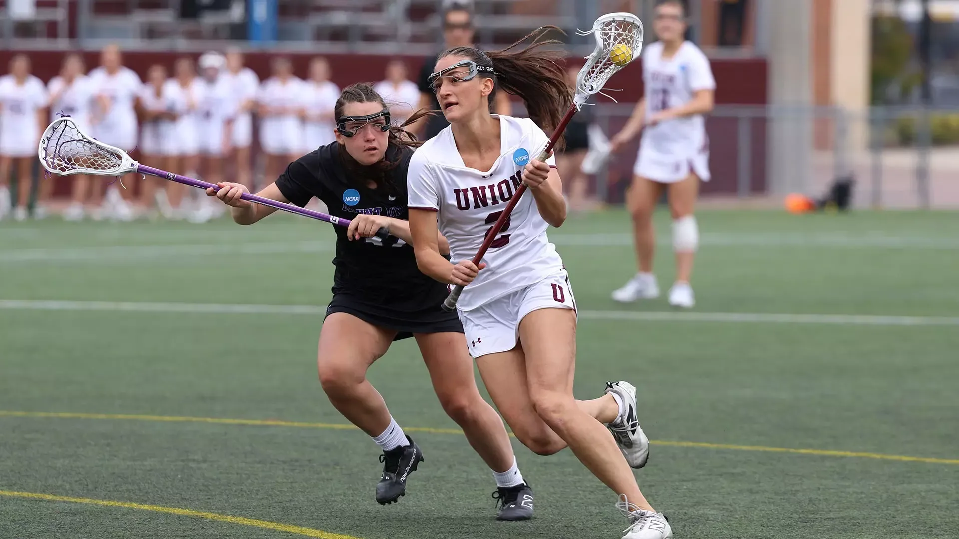 A Union lacrosse player runs by an opponent on the way to scoring a goal.