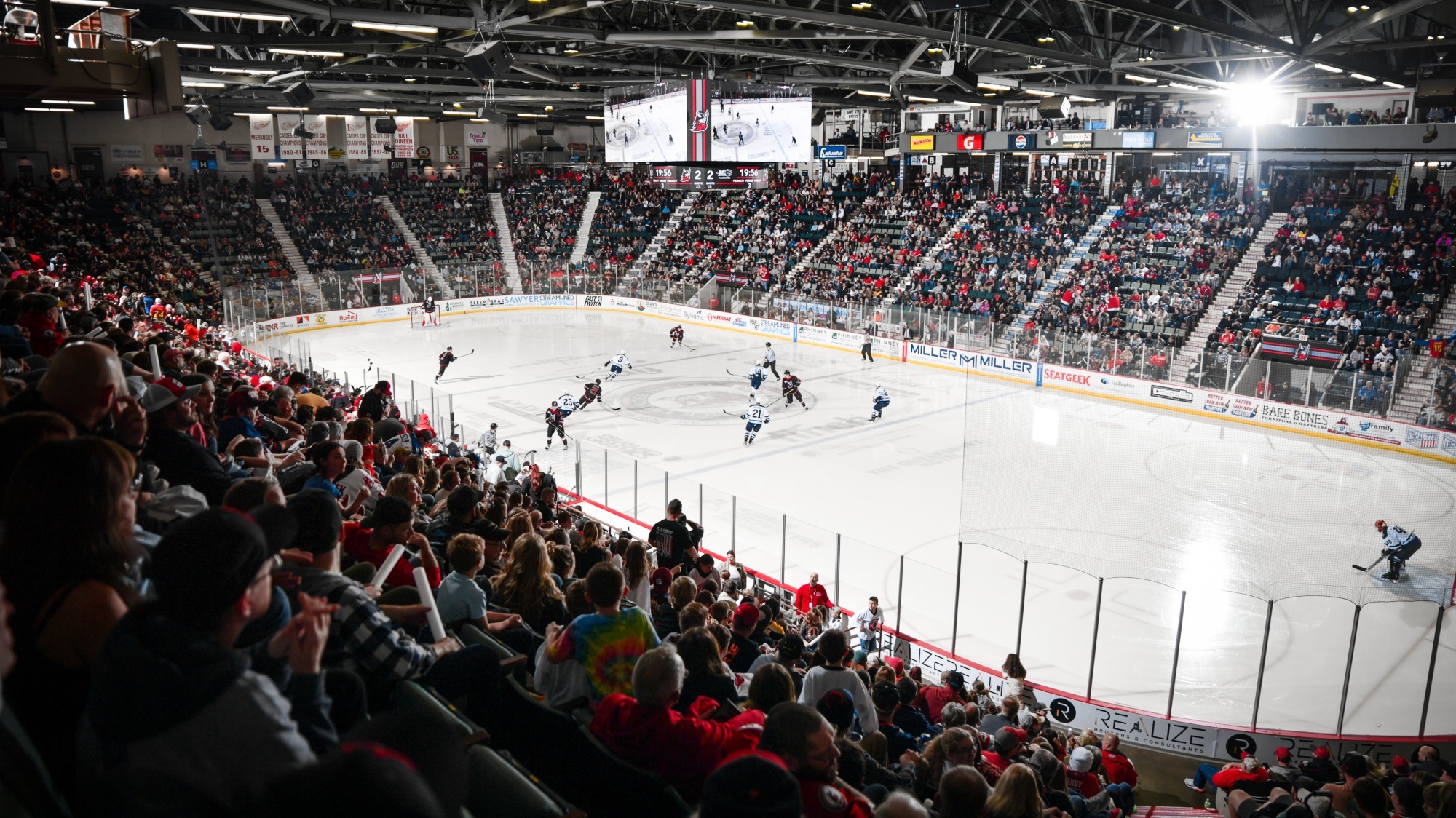 A hockey arena filled with fans and skaters on the ice.
