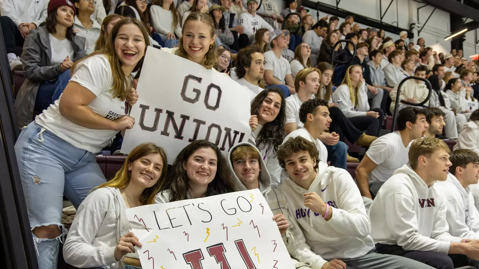 Fans smiling at the camera and holding up signs that say 