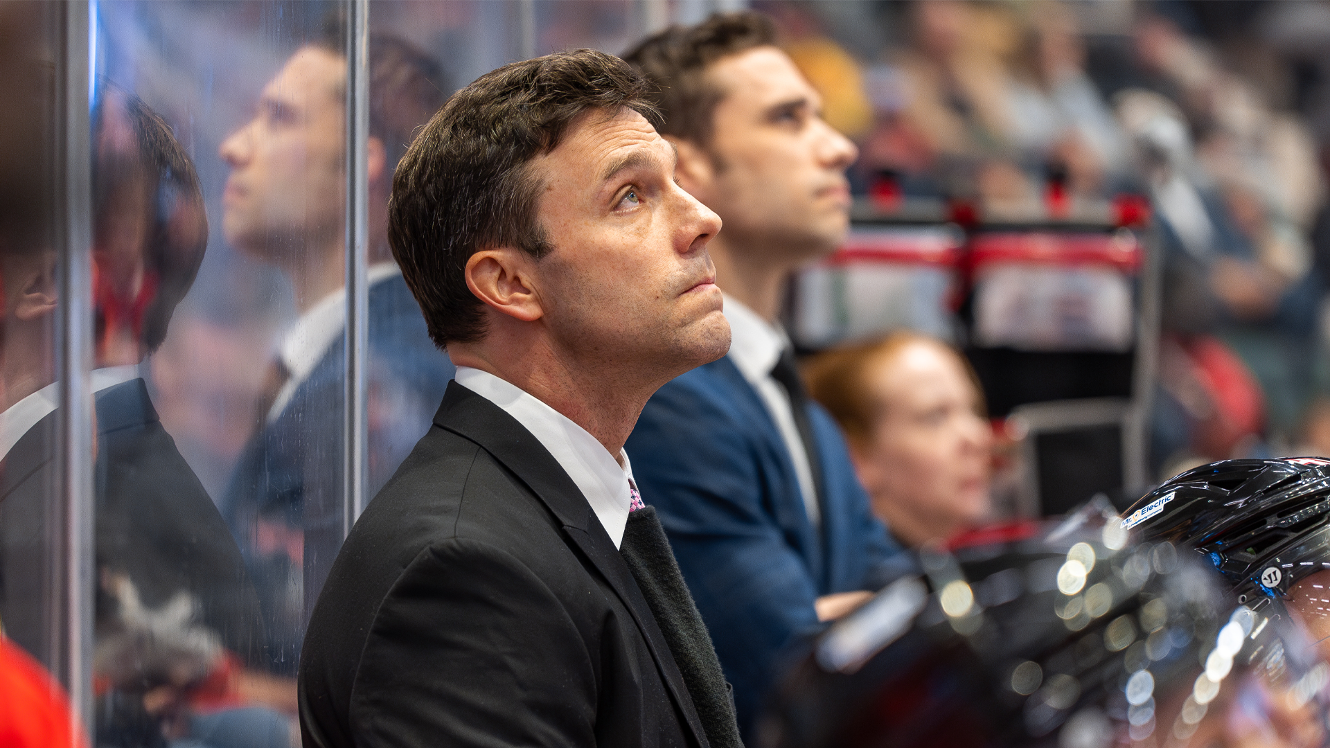 a man in a black suit photographed from his side profile, looking up