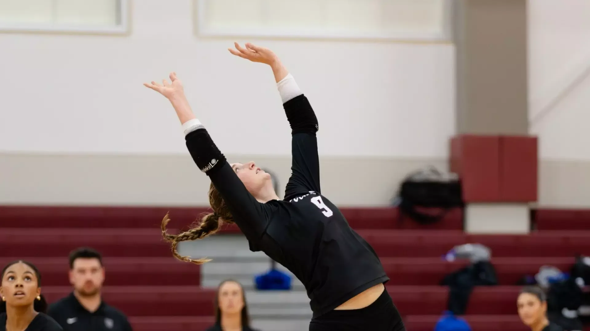 a women's volleyball player setting a ball