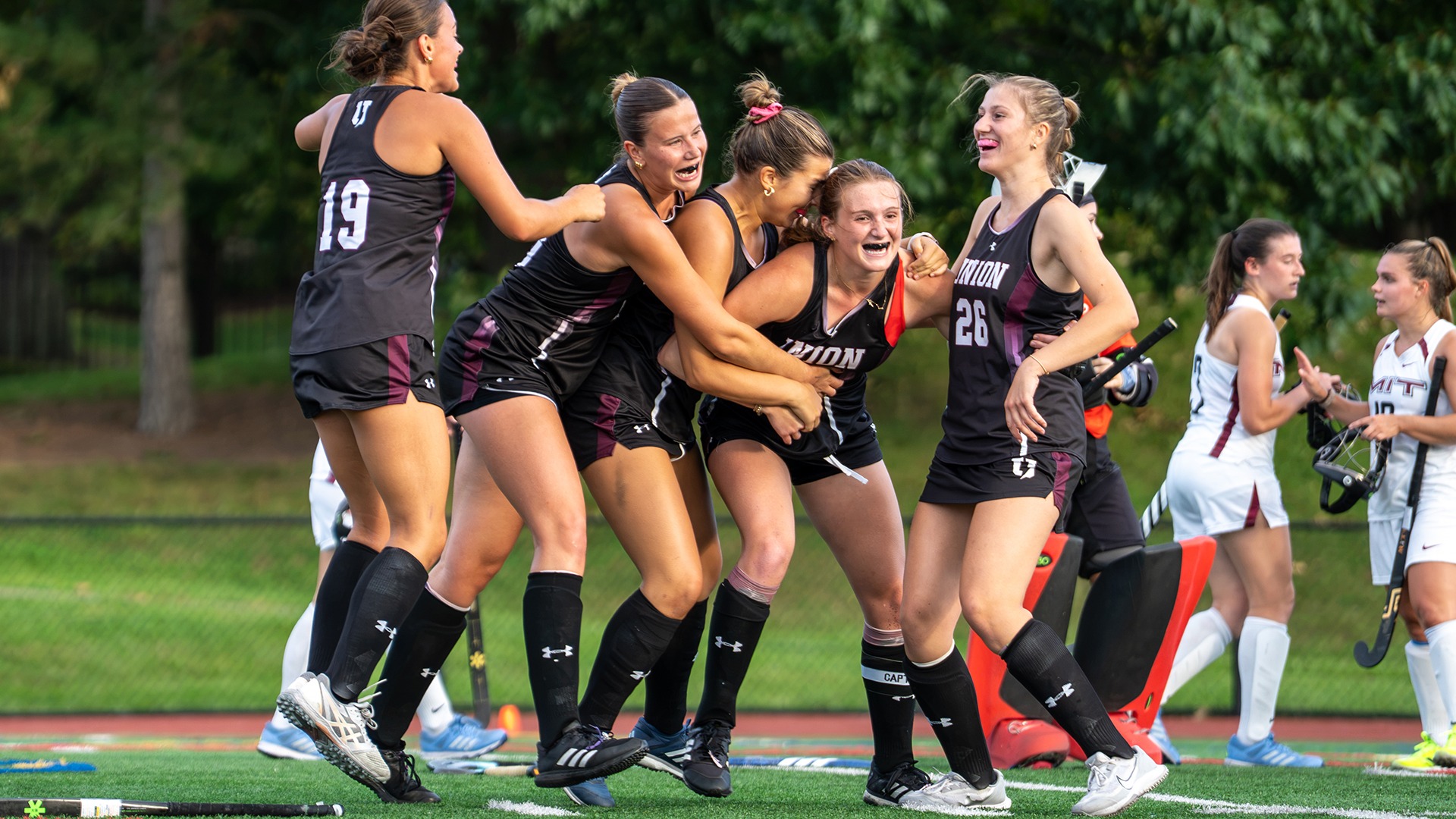 Field hockey players celebrating a game-winning goal