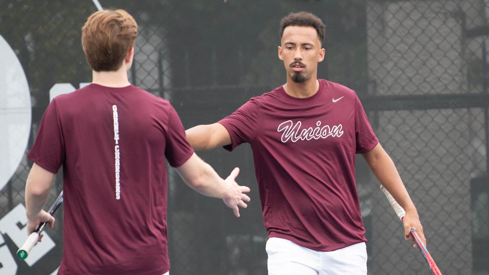Tennis doubles partners high-fiving after a point.