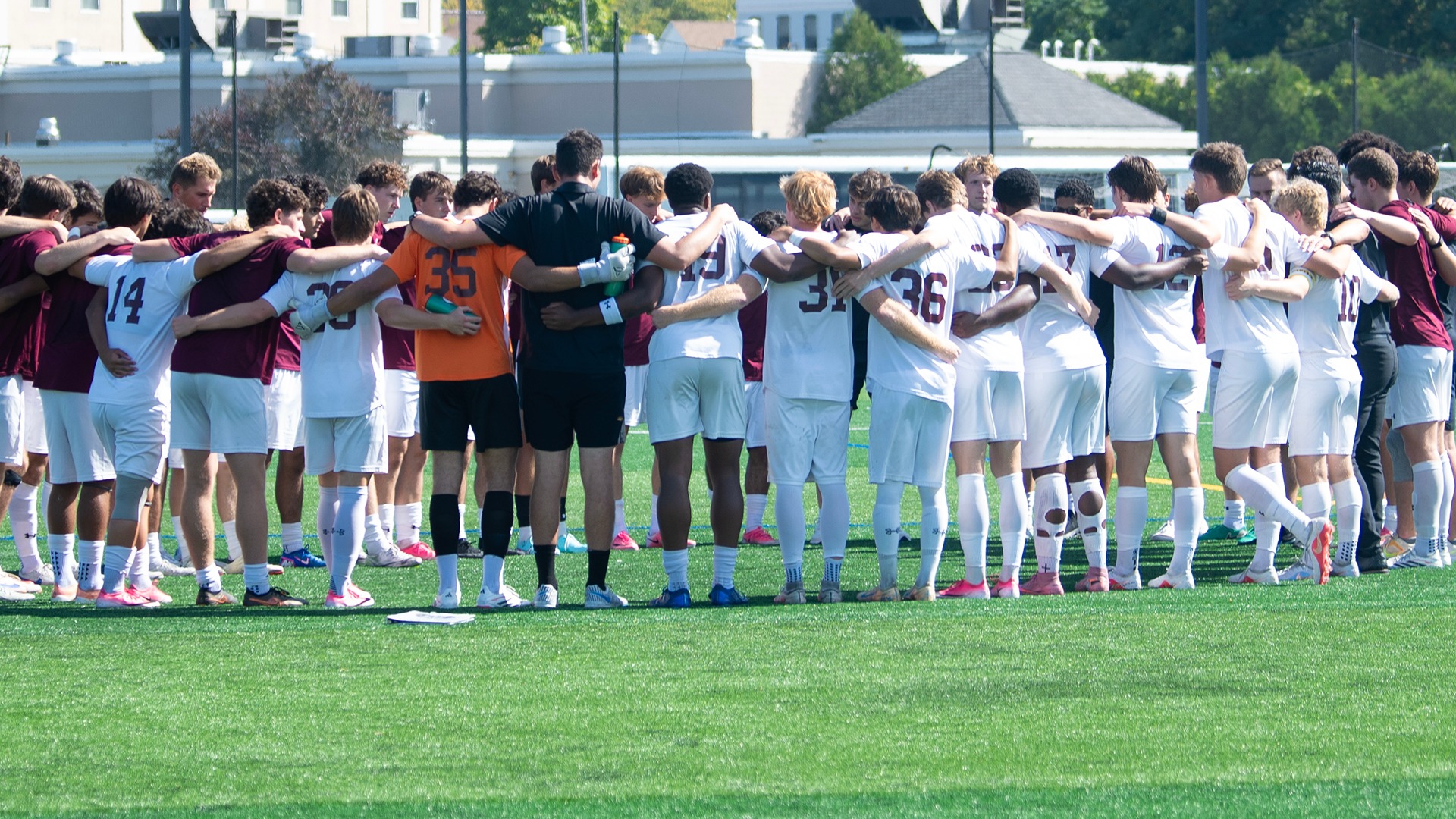 Soccer players huddling together on a field.