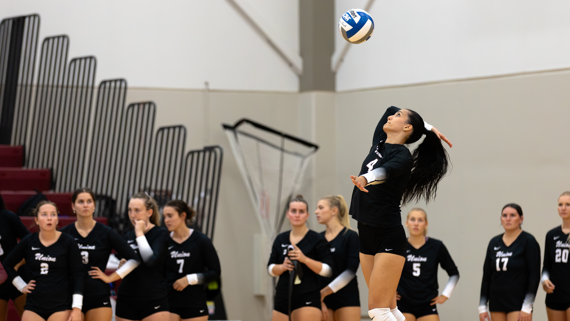 a women's volleyball player serving the ball