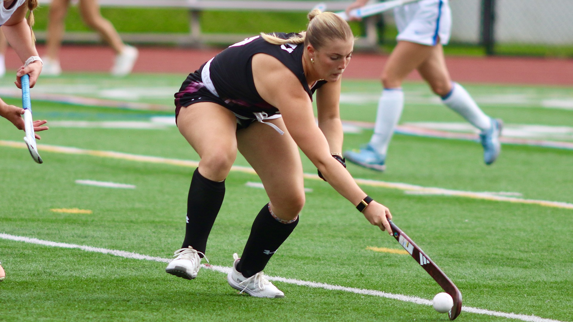 A field hockey player stickhandling on the backhand.