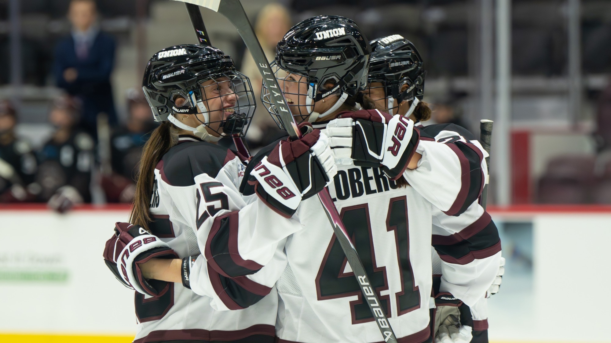 Union women's hockey players smiling and hugging after a goal.