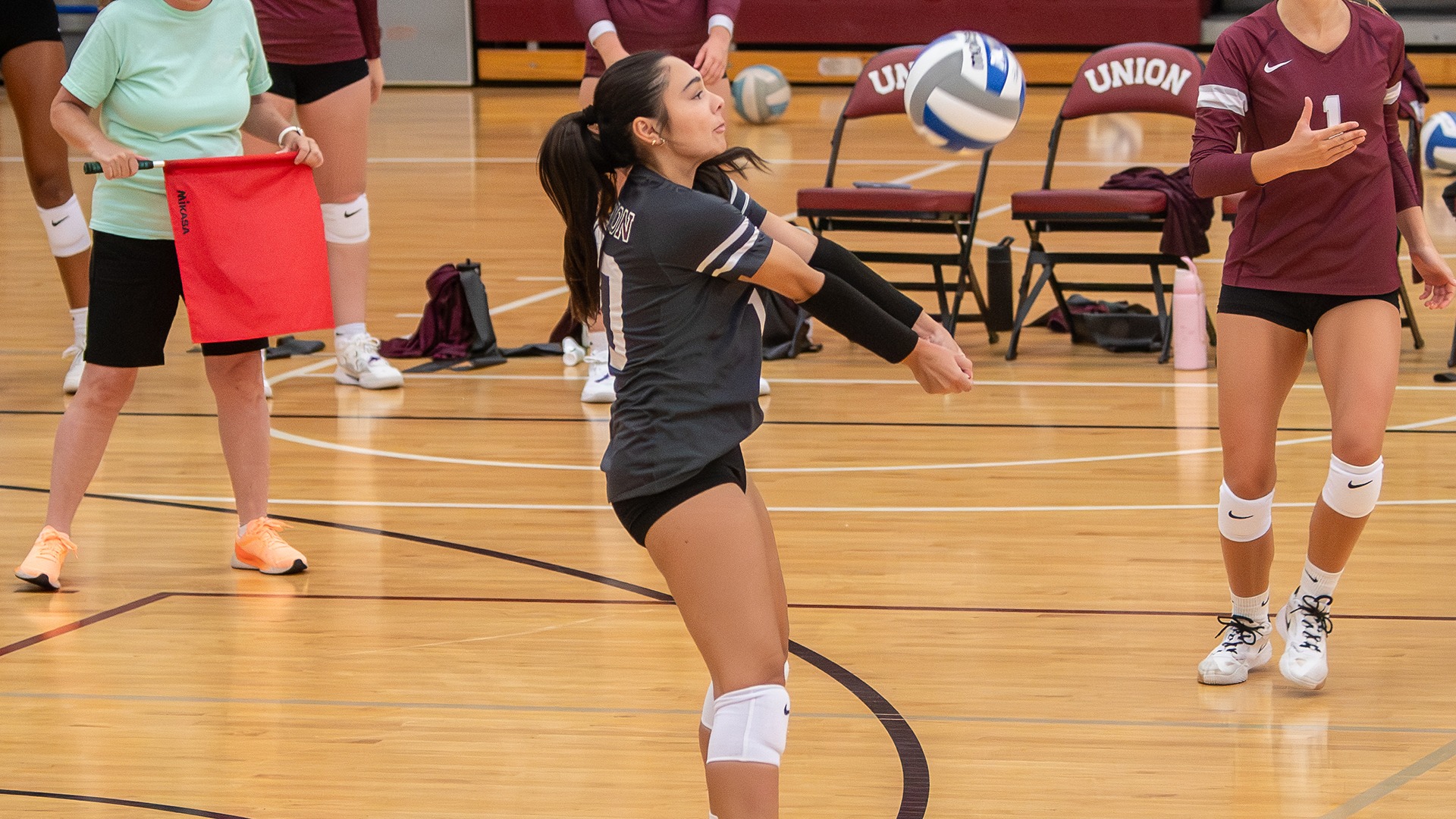 A women's volleyball player digs an attack.