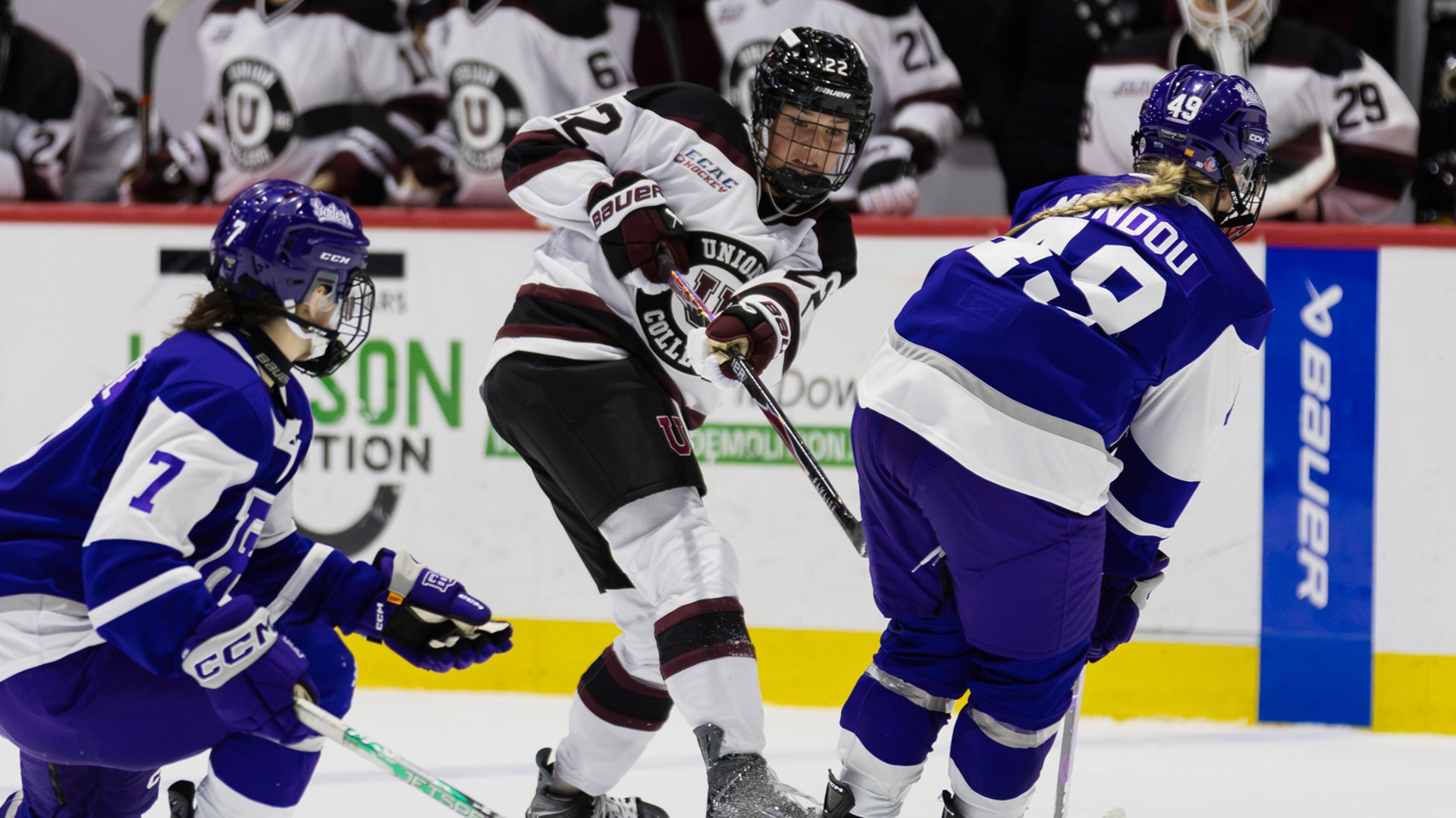 A Union women's hockey player watches her pass so between two defenders.