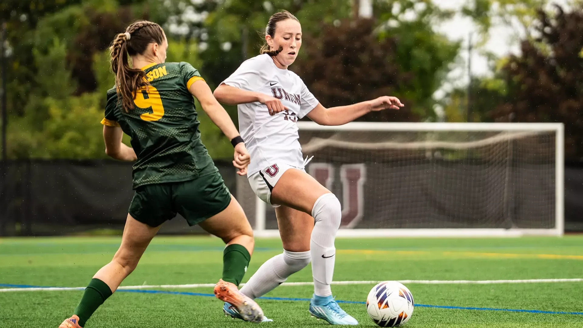 A Union women's soccer player pokes the ball past a defender.