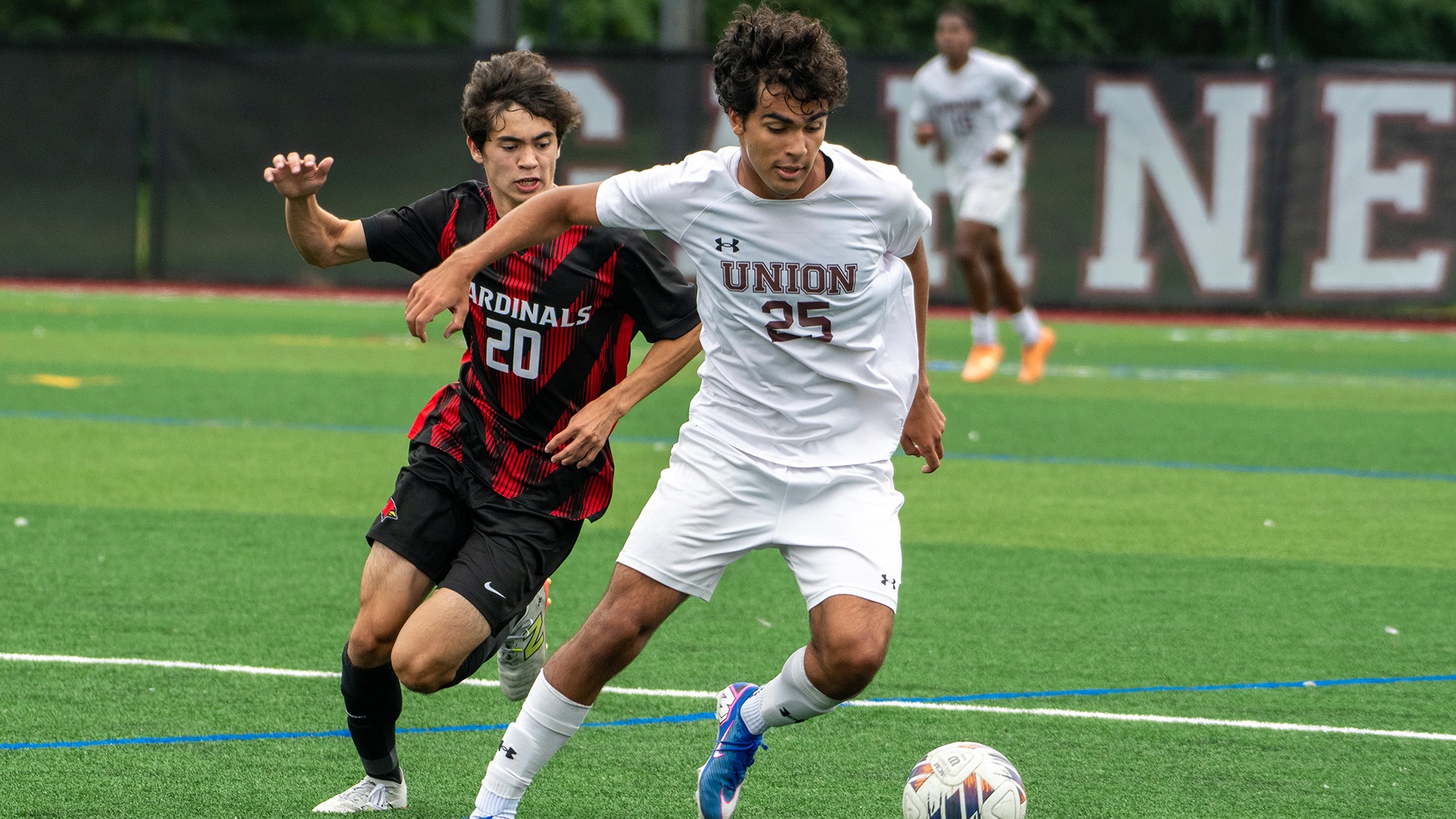 A Union men's soccer player dribbles away from a defender.