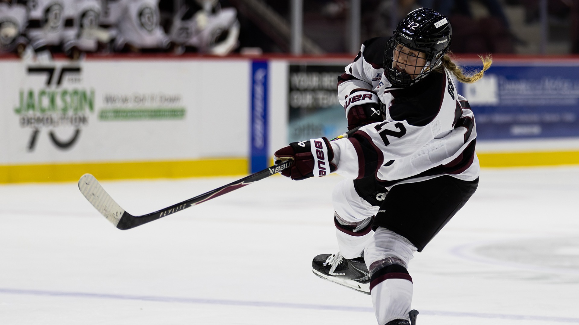 A hockey player following through on a wrist shot.
