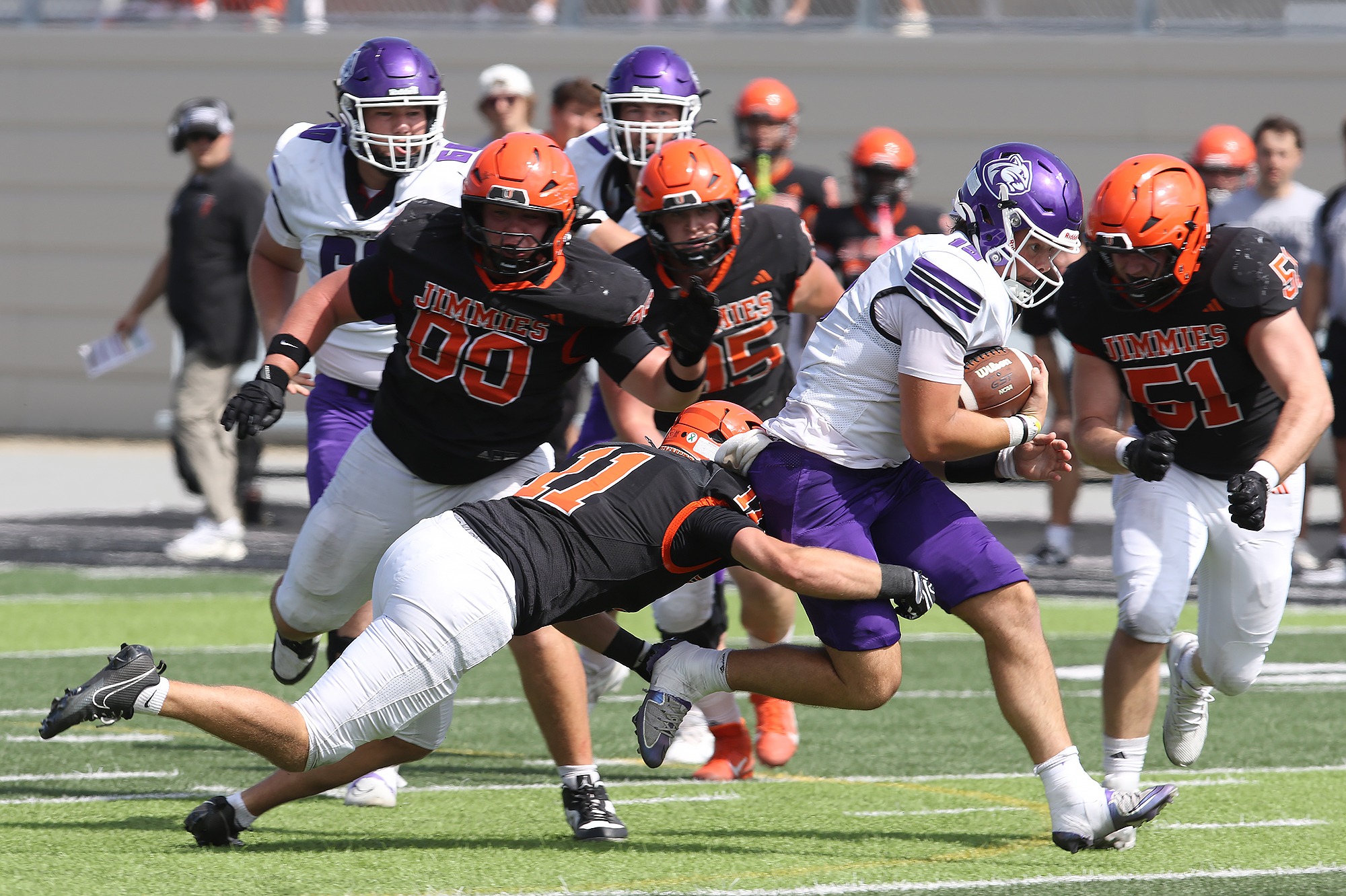 A host of Jimmies including Tanner Chaffee (11), Gus Werremeyer (99), Ethan Gall (95), and Antonio Bernardini (51) move in for a tackle on the Cougars' quarterback Bennet Brueck on Saturday, Sept. 5, 2026, at Charlotte and Gordon Hansen Stadium.