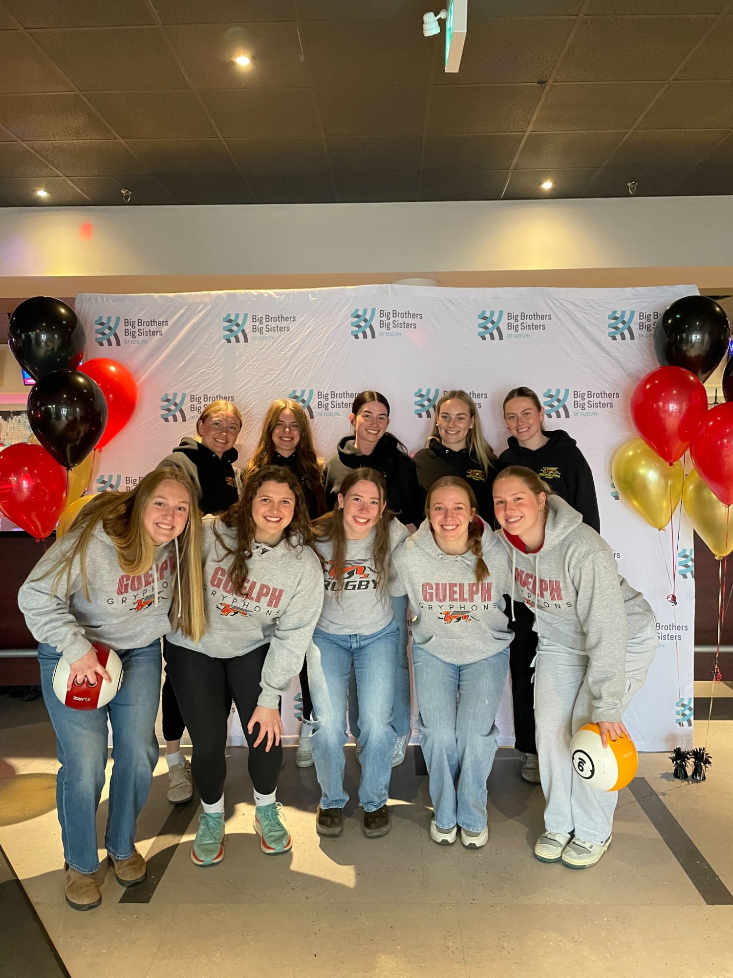 Members of a Gryphon team smiling behind Bowl for kids sake event back drop