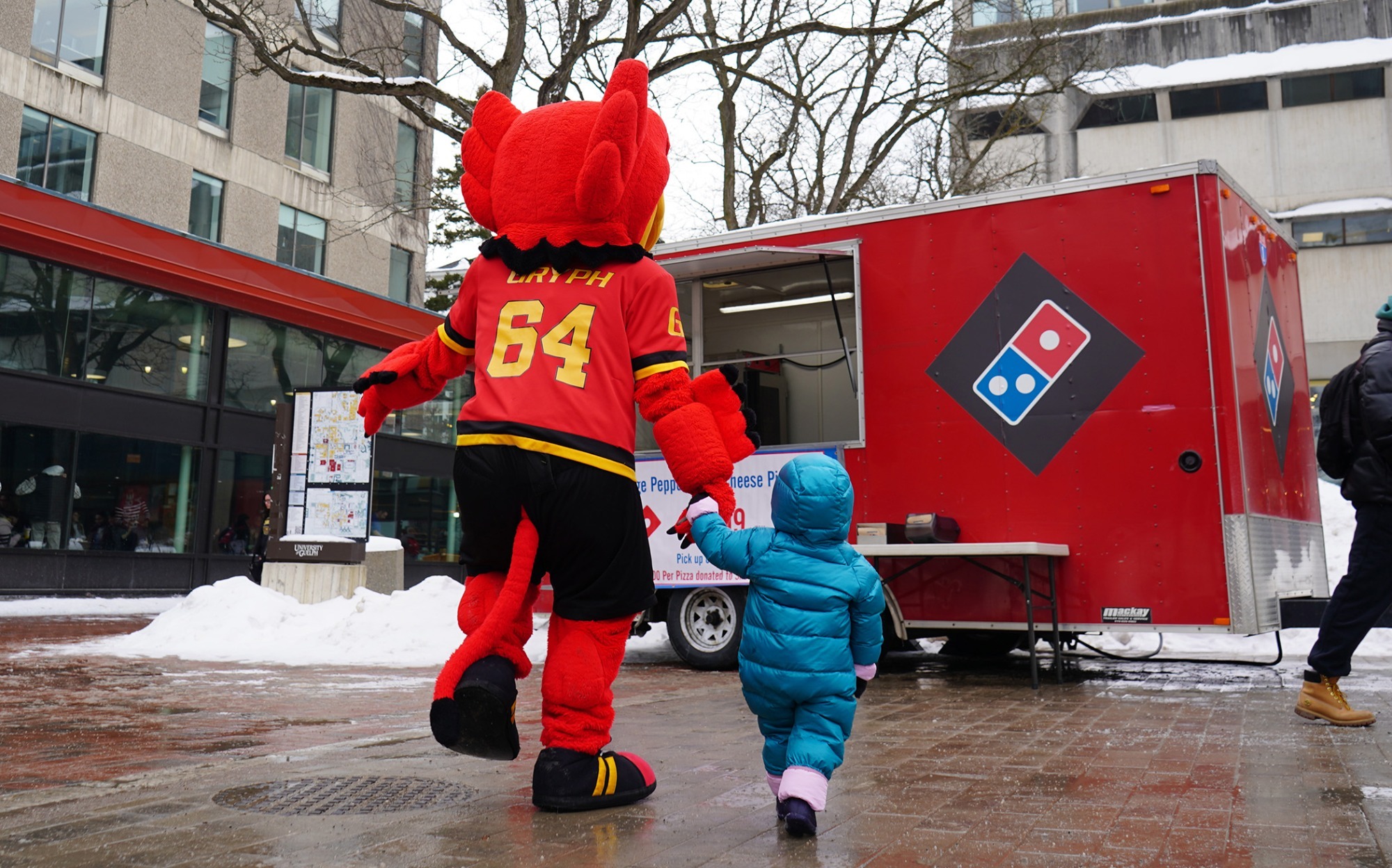 gryphon mascot walking with girl towards the Domino's pizza truck