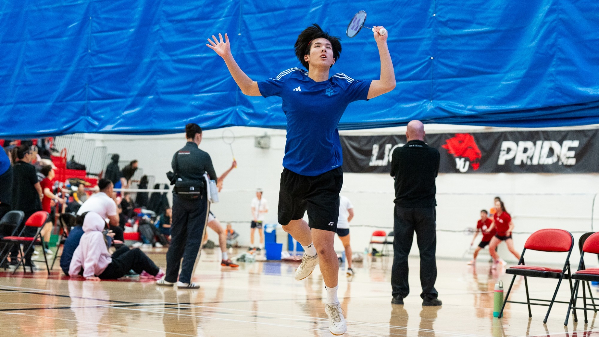 Joshua Nguyen jumping with a badminton racket in hand.