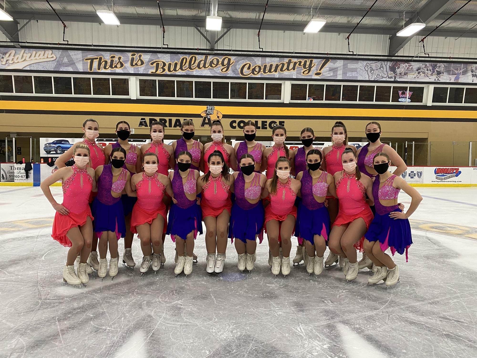 Adrian College pose for team photo in pink and purple costume with face coverings