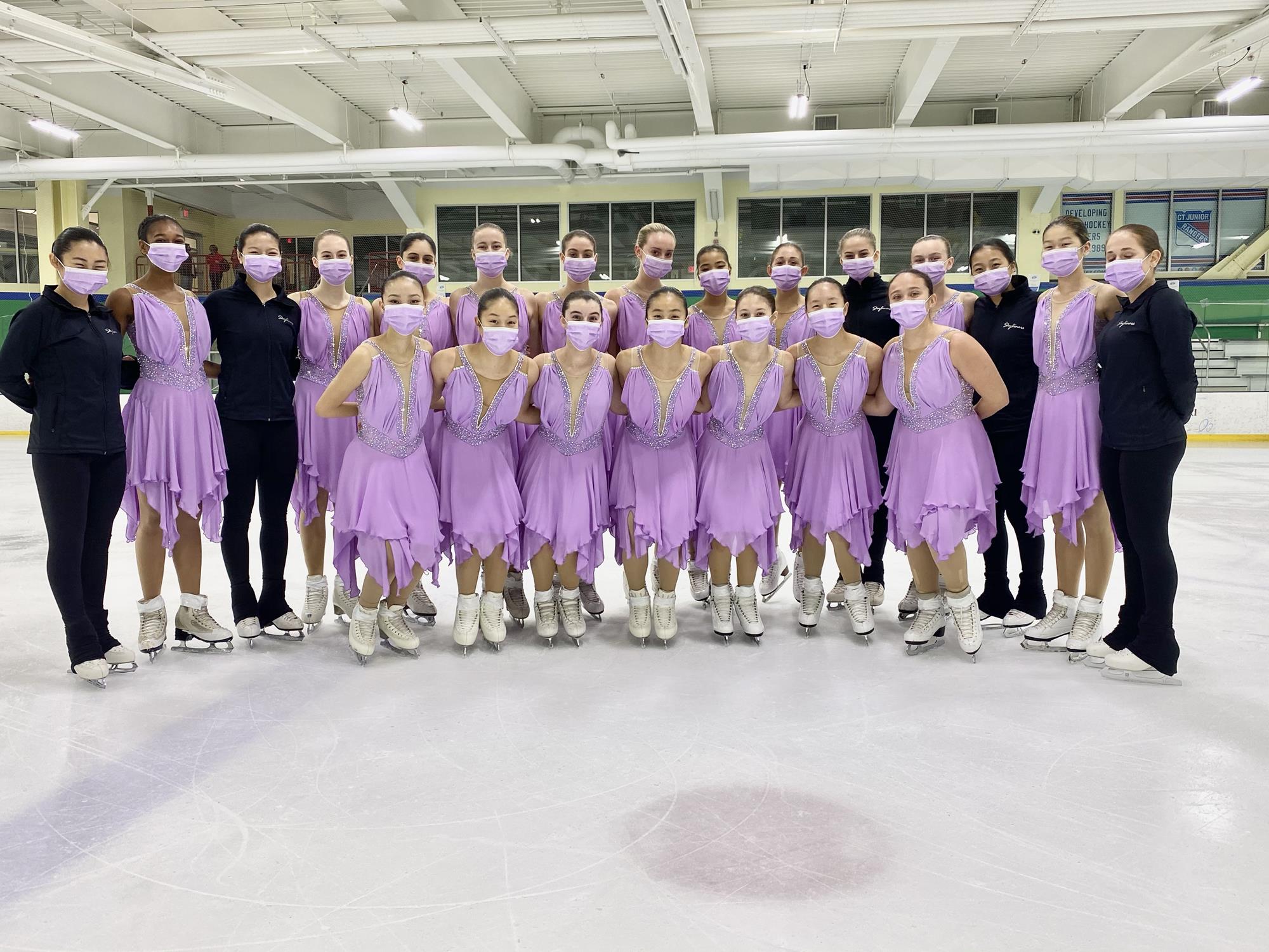 Skyliners Jr pose with team in lilac costumes and face coverings