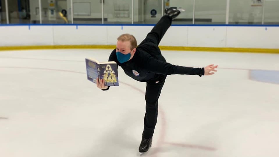 Andrew Sass reads his book while doing a spiral on the ice.