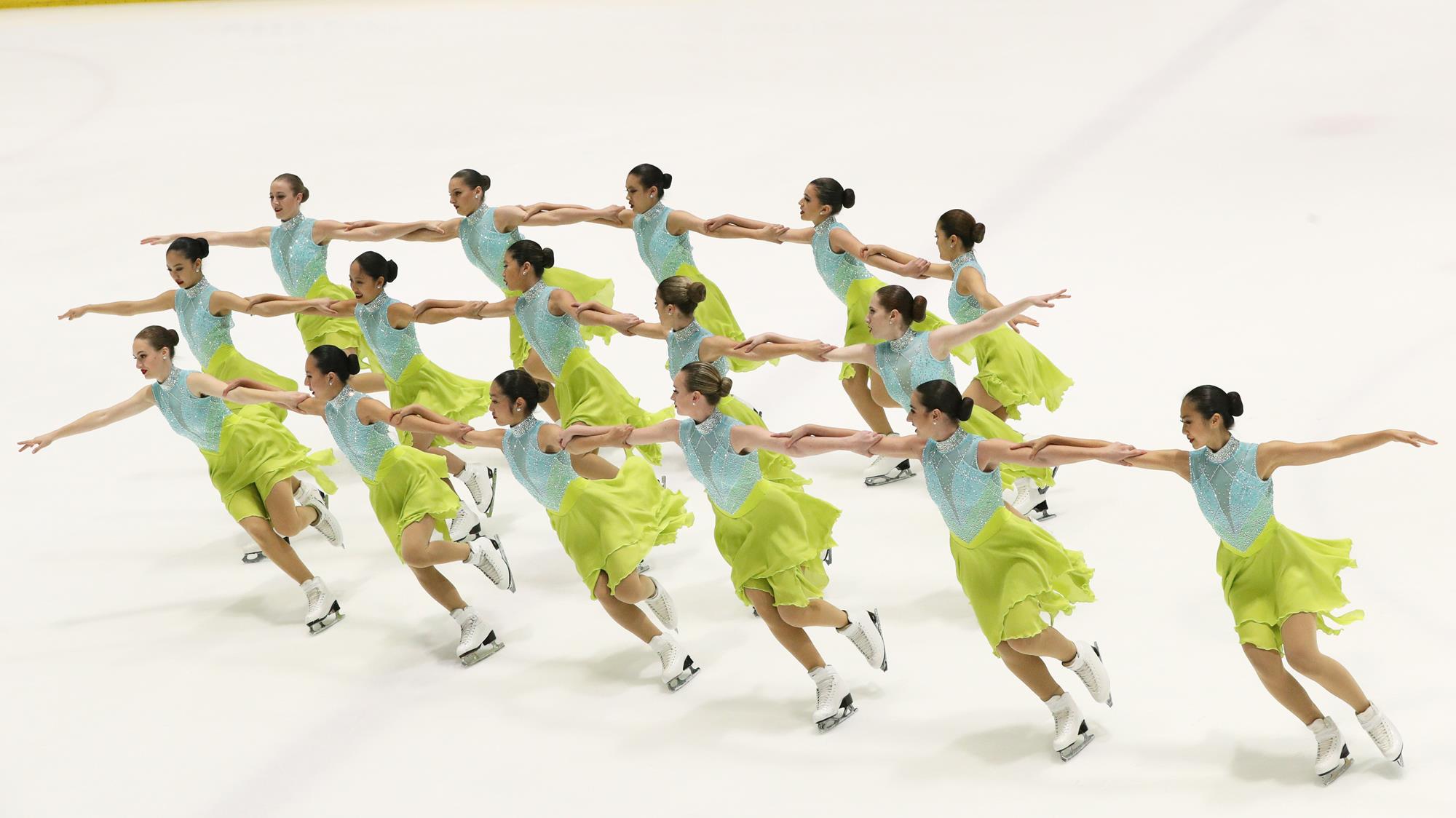 Skaters in three rows holding arms moving to the left.