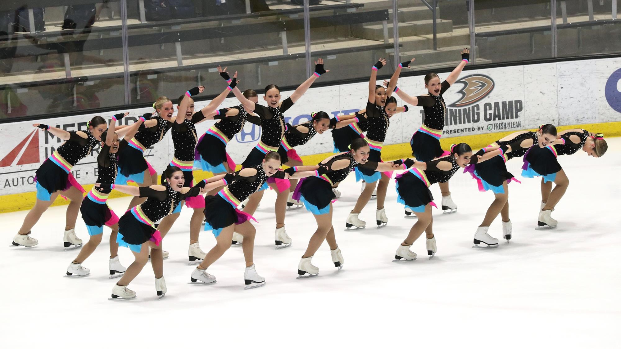 Teams Elite in black dresses with bright underlaid colors perform in unison