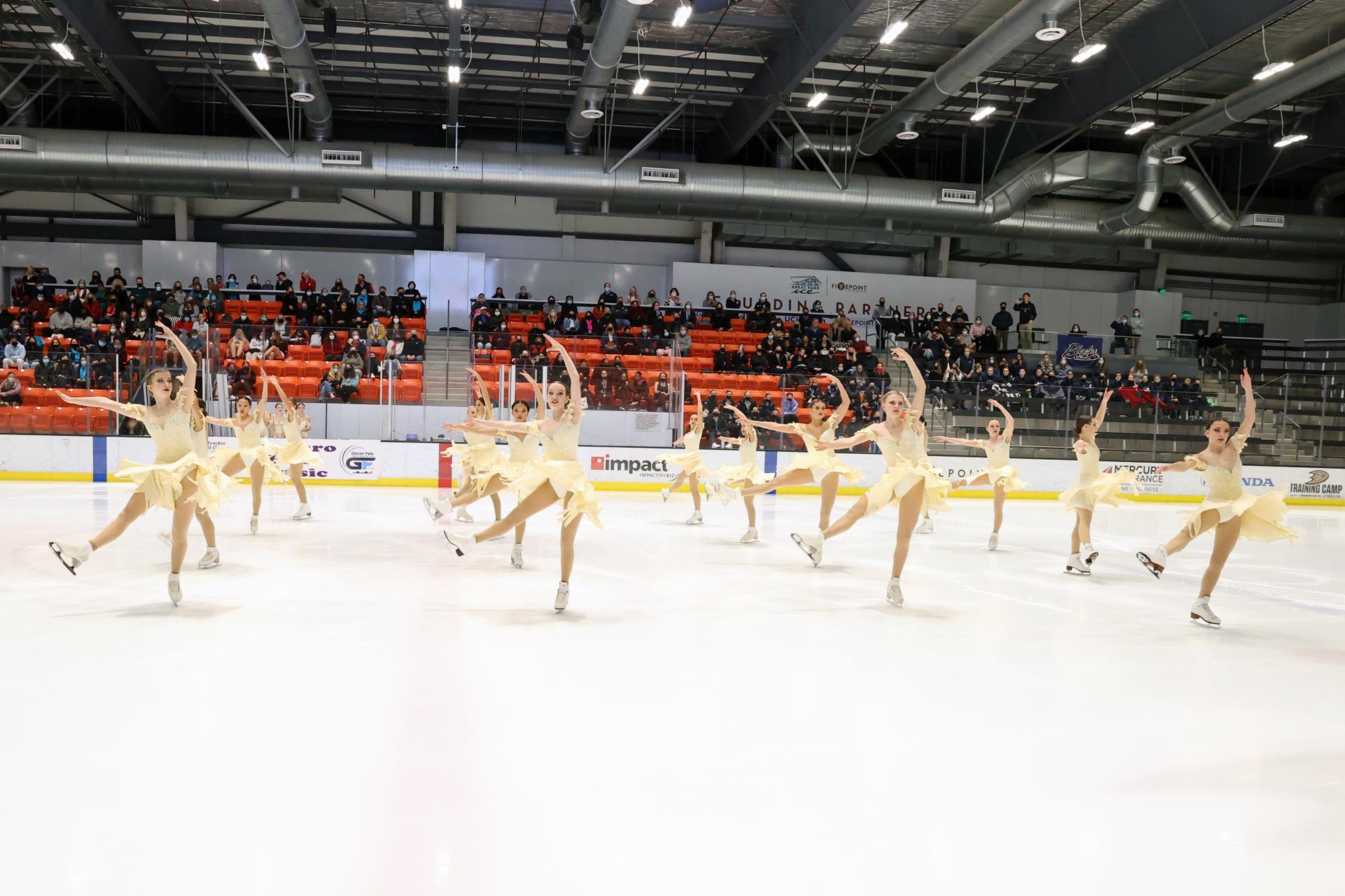 The Northernettes, in yellow dresses, in four rows performing a spin.