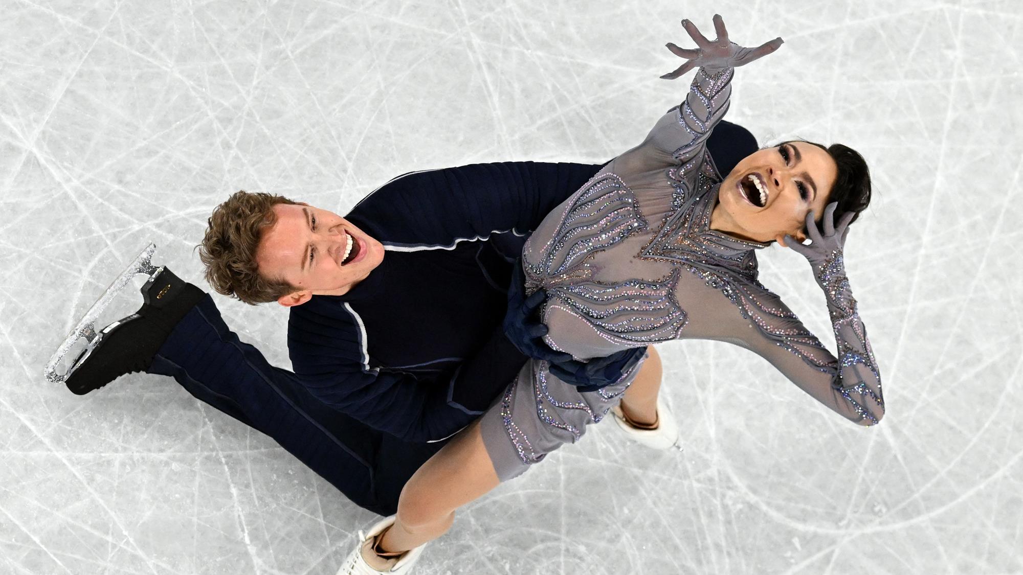 Madison Chock and Evan Bates look up toward the camera in their finishing pose, excited about their results.
