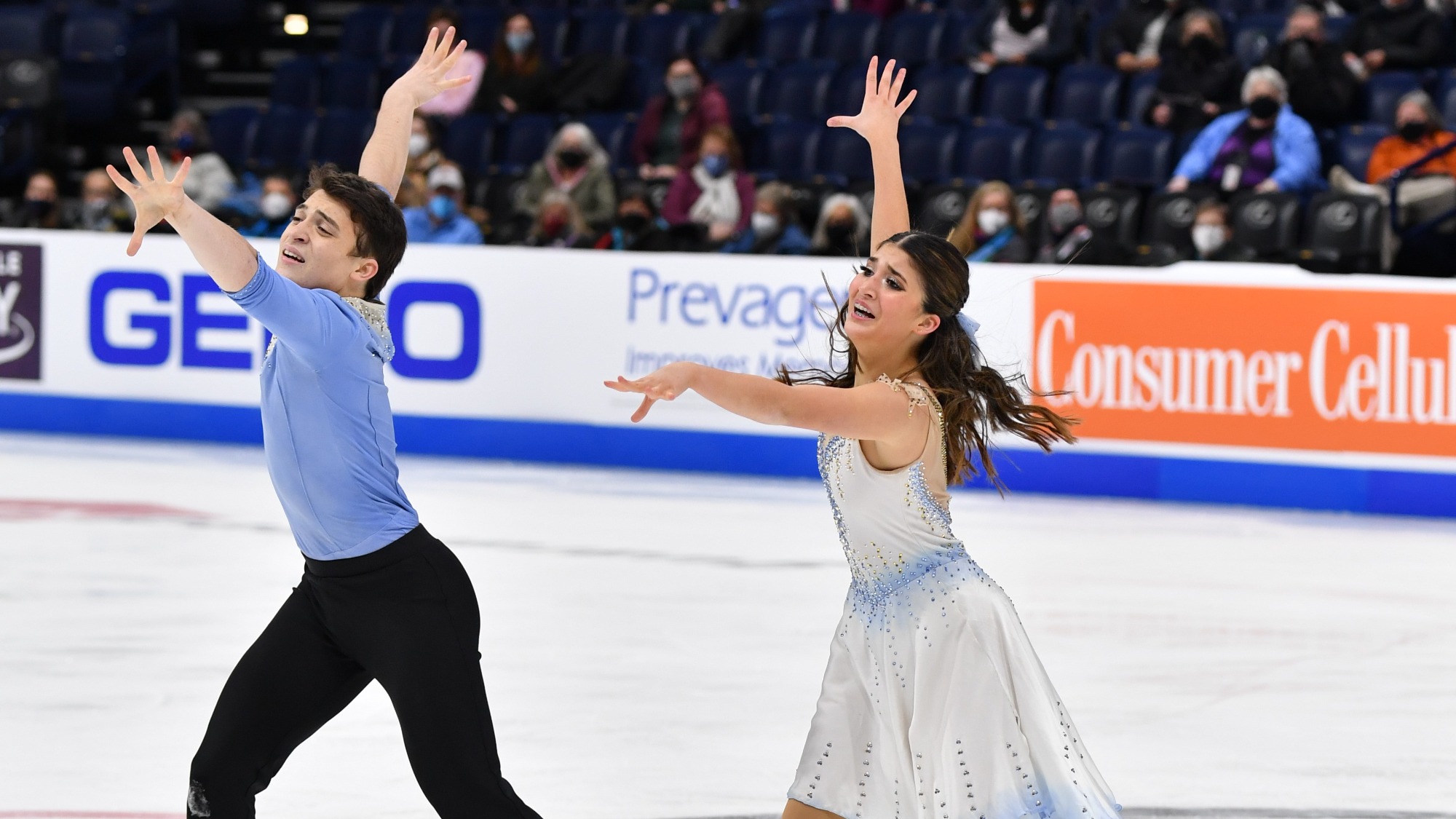 Ethan Peal (left) and Elliana Peal (right) performing at the 2022 U.S. Championships, their arms in synch - their right arm raised behind and their left straight out in front.