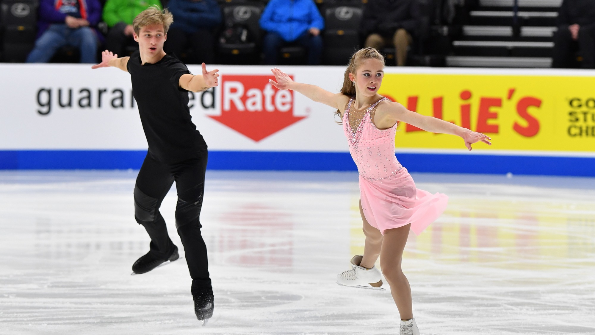 Leah Neset (right) and Artem Markelov (right) skate forward, parallel to each other.