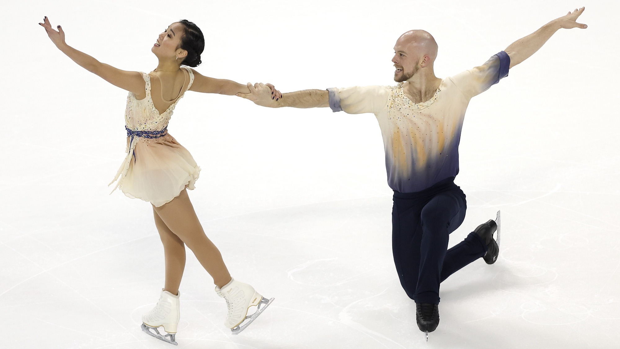 Ellie Kam and Danny O'Shea hit their ending pose. She stands to the left, facing away from him, holding his hand with her  right arm and reaching out with her left. He kneels, holding her hand with his left arm , his right arm out behind him. 